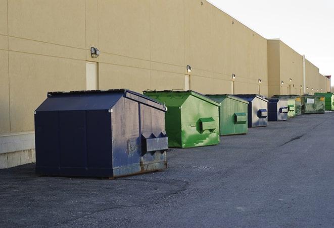 a construction worker empties a wheelbarrow of waste into the dumpster in Angelus Oaks